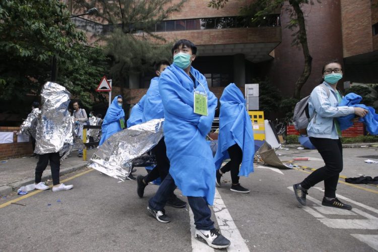 Injured protesters wrapped in blankets, walk through the campus of the Hong Kong Polytechnic University in Hong Kong, Tuesday, Nov. 19, 2019. About 100 anti-government protesters remained holed up at the Hong Kong university Tuesday as a police siege of the campus entered its third day. 