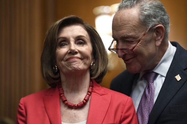 House Speaker Nancy Pelosi of Calif., left, and Senate Minority Leader Sen. Chuck Schumer of N.Y., right, listen as they wait to speak at an event Tuesday on Capitol Hill in Washington.
