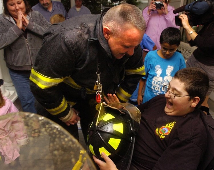 Winslow firefighter Scott Higgins awards Casey Grant a genuine firefighters helmet in August 2007. Higgins died on Monday after serving 18 years on the Winslow Fire Department.