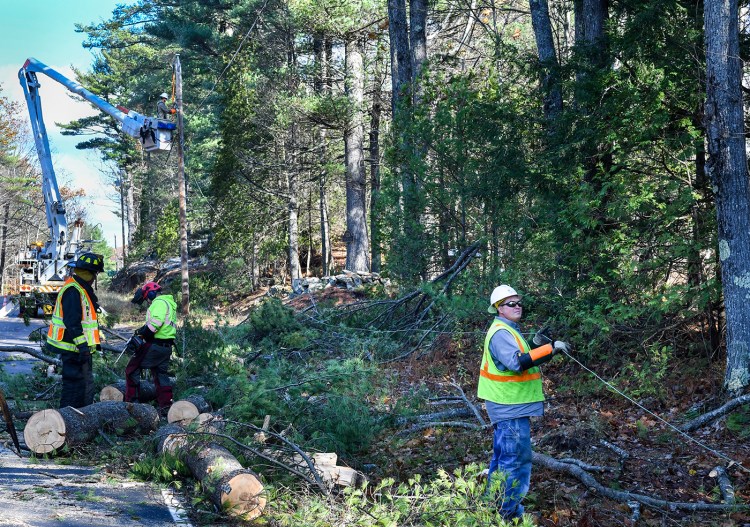 Monmouth firefighters assist a Lucas Tree crew Friday as it works to clear a fallen tree from Route 135 as Central Maine Power workers repair electrical wires in town. High winds Thursday night into Friday morning caused many tree limbs to fall on power lines across the region, cutting power to thousands. 
