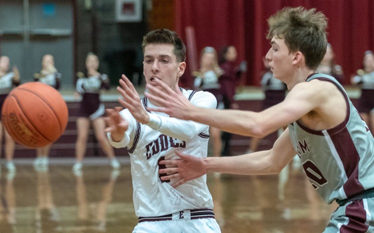 Edward Little's Austin Brown, left, passes to a teammate under the basket while being defended by Windham's Eric Weisser during the first quarter of Friday night's game in Auburn.