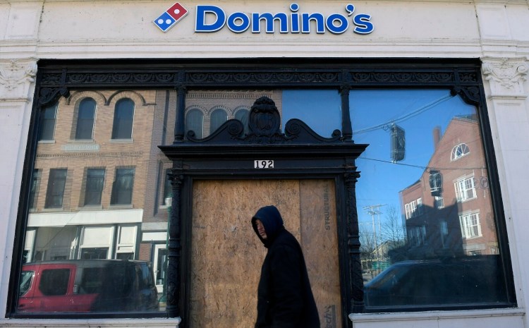 The Domino's Pizza building, with plywood covering the front door, is seen Dec. 24 in downtown Gardiner. A year after a fire gutted the structure, the owner is rebuilding with plans to re-open with a few months.