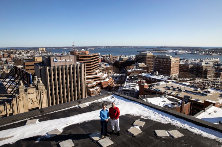 Chris Rhoades, left, and Drew Preston pose for a photo on the roof of the Time & Temperature Building in downtown Portland on Friday. The developers bought the building last year and say they want to bring the city's most recognizable building "back to its glory days."