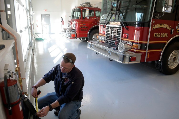 Capt. Doug Ebert hangs  a digital dispatch system Tuesday in the bays of the new Farmingdale Fire Station. Kennebec Journal photo by Andy Molloy