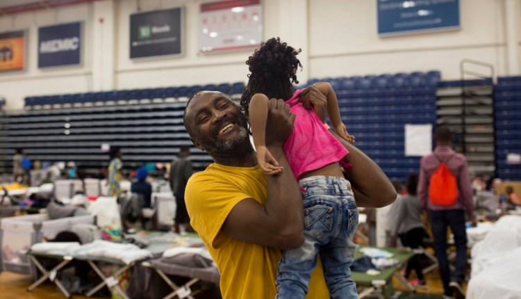In a June 2019 photo, Coco Ikoko plays with a friend's child at the Portland Expo, where he lived temporarily with other asylum seekers from the Congo and Angola. Ikoko fled his home in the Congo after he was informed of his pending arrest because of his involvement in an underground political group. The influx of immigrants, many to Maine's biggest city, is changing the state's demographics rapidly.