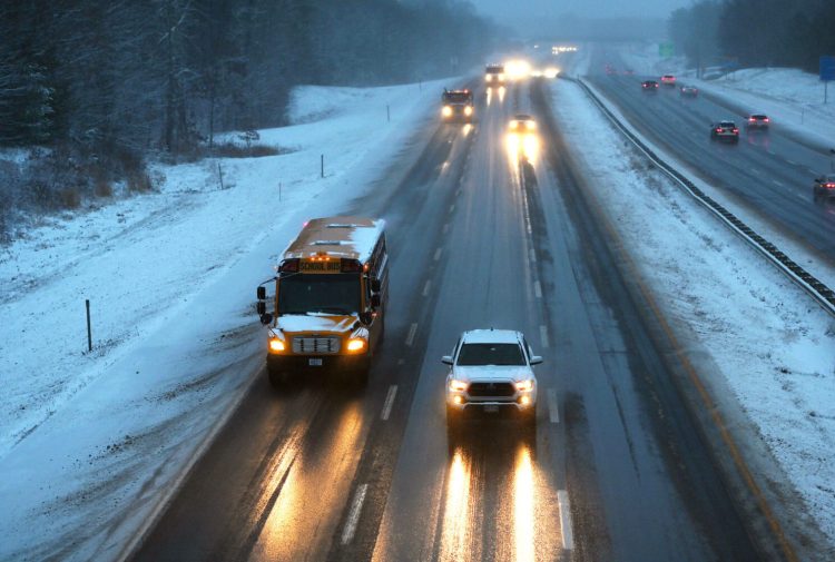 A school bus moves slowly on the Maine Turnpike in Saco as the weather slows down the morning commute Monday. 