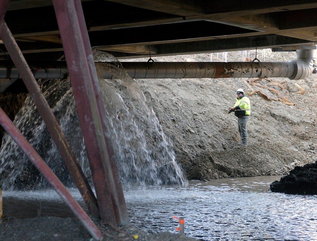 A worker examines a water main that ruptured Thursday beneath the Bridge Street bridge in Gardiner. Witnesses said an excavator that was working accidentally hit the water pipe, flooding the area beneath the bridge. The construction is part of a Maine Department of Transportation project to rebuild both bridges in Gardiner spanning Cobbossee Stream.