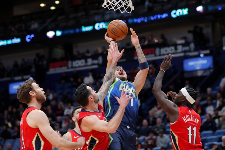 Luka Doncic, center, shoots between New Orleans defenders Nicolo Melli, left, and JJ Redick and Jrue Holiday during's Tuesday's game. 
