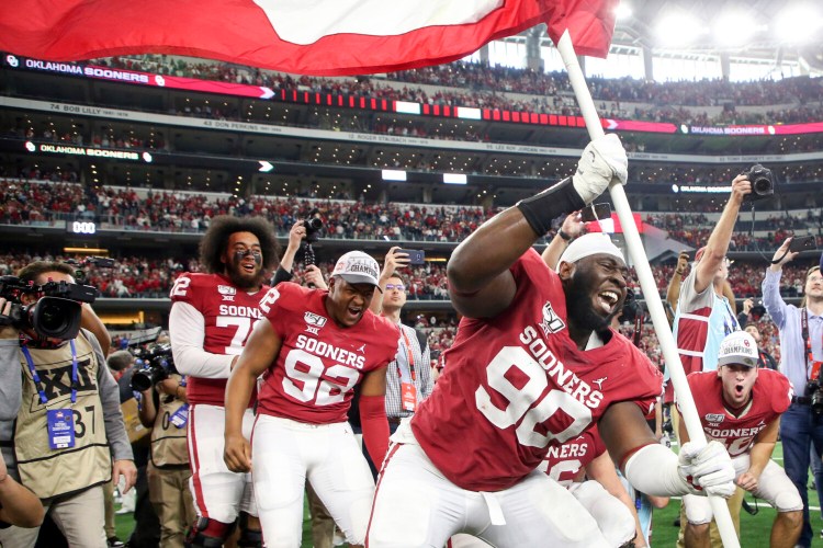 Oklahoma defensive lineman Neville Gallimore plants a University of Oklahoma flag after the Sooners' 30-23 overtime win over Baylor in for the Big 12 Conference championship game on Saturday in Arlington, Texas.