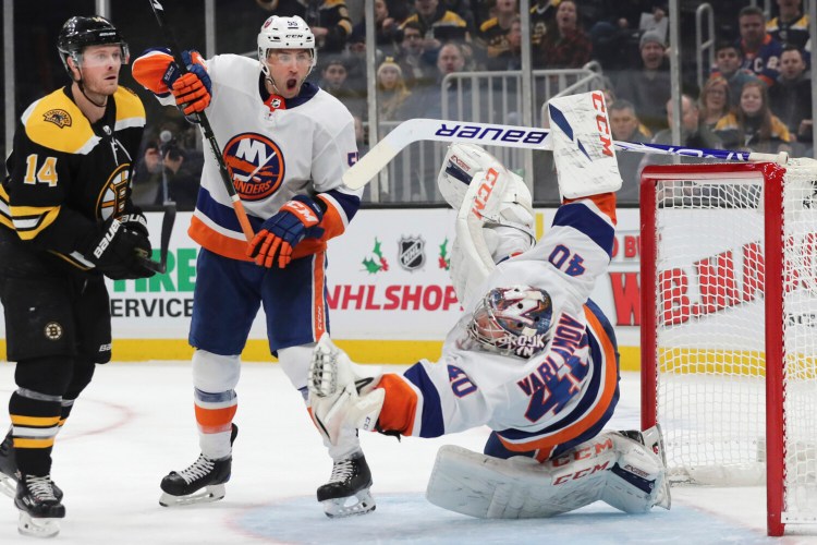 New York goaltender Semyon Varlamov falls after making a glove save, as Boston’s Chris Wagner, left, and Islanders defenseman Johnny Boychuk look on.