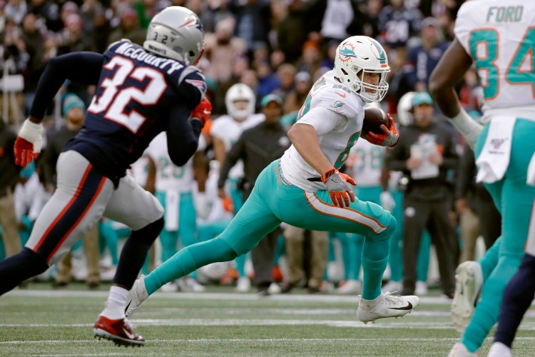 Miami Dolphins tight end Mike Gesicki runs from New England Patriots safety Devin McCourty, left, after catching a pass in the second half of the Dolphins' 27-24 win Sunday in Foxborough, Mass.