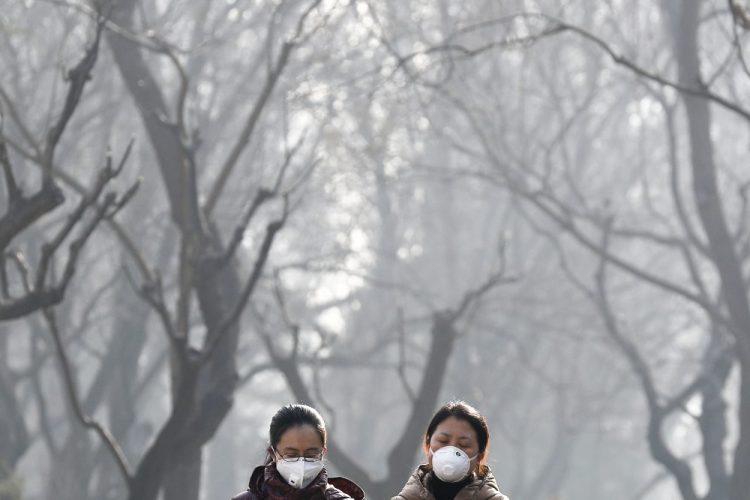 FILE - In this Dec. 19, 2016, file photo, women wearing masks to protect themselves from air pollution walk through Ritan Park shrouded by dense smog in Beijing. Scientists say emissions worldwide need to start falling sharply from next year if there is to be any hope of achieving the Paris climate accord’s goal of capping global warming at 1.5 degrees Celsius (2.7 Fahrenheit). (AP Photo/Andy Wong, File)