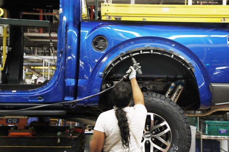 An assemblyman works on a 2018 Ford F-150 truck at the Ford Rouge assembly plant, in Dearborn, Mich., last year. Ford Motor Co. is investing $1.45 billion to build new pickup trucks, SUVs, and electric and autonomous vehicles. At the Dearborn truck plant, $700 million will be invested. 
