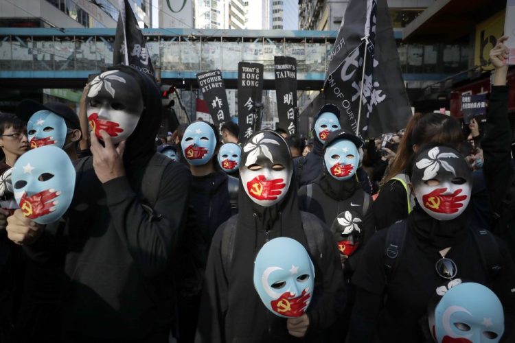 Masked pro-democracy protesters march Sunday in Hong Kong, marking six months of demonstrations.