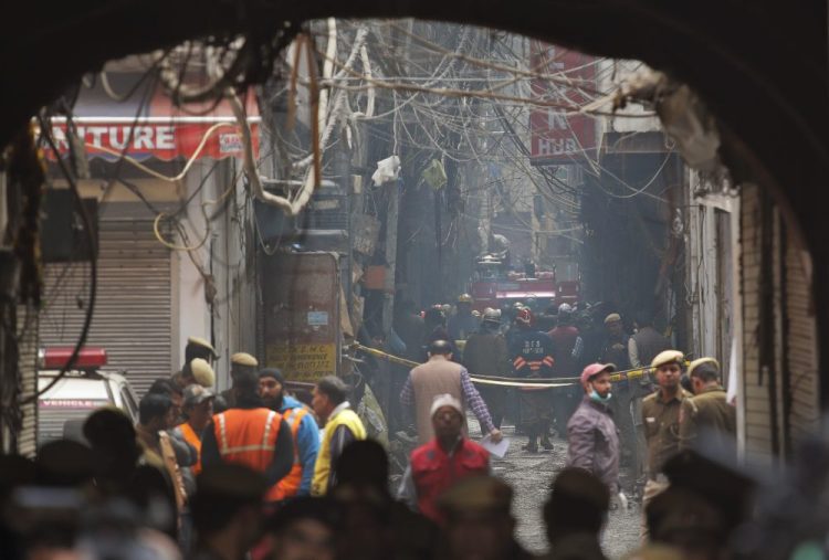 A fire engine stands by the site of a fire Sunday in an alleyway, tangled in electrical wire and too narrow for vehicles to access, in New Delhi, India. Dozens of people died on Sunday in a devastating fire at a building in a crowded grains market area in central New Delhi, police said.