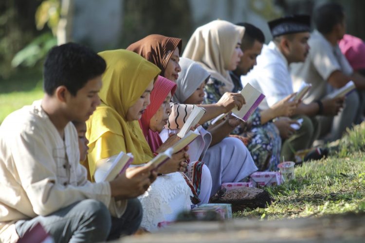 People read the Quran as they pray at a mass gravesite for the victims of the Indian Ocean tsunami, during the commemoration of the 15th anniversary of the disaster in Banda Aceh, Indonesia, on Thursday.