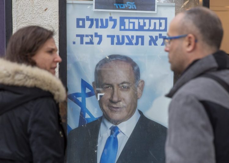 People look at a poster of Israel Prime Minister and governing Likud party leader Benjamin Netanyahu at a voting center in the northern Israeli city of Hadera, on Thursday. Netanyahu won the primary election, retaining control of his party.