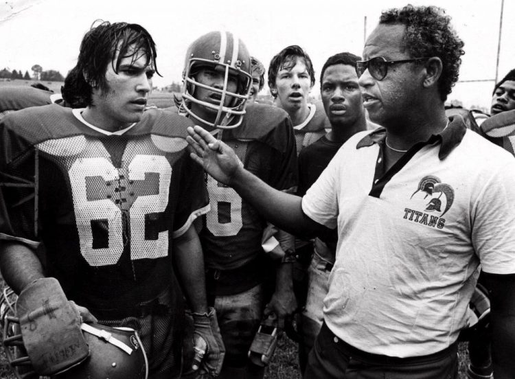 T.C. Williams High School football coach Herman Boone, right, during a break at summer camp, with guard Johnny Colantuoni, (62) and John Vaughn, center. Boone, the Alexandria, Va., high school football coach who inspired the movie “Remember the Titans,” has died.