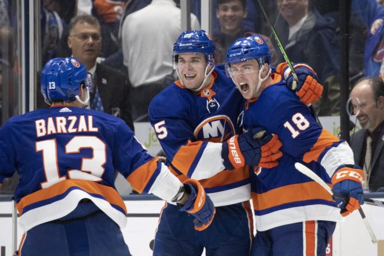 New York left wing Anthony Beauvillier (18) celebrates his goal in overtime goal to give the Islanders a 3-2 win over the Buffalo Sabres with teammates Mathew Barzal (13) and Devon Toews, center, on Saturday in Uniondale, New York.