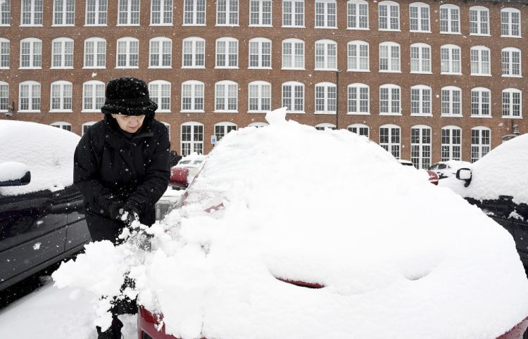 Sue Baker clears snow from her car at the Sterling Lofts apartments Tuesday,  in Attleboro, Mass. The area received several new inches of snow overnight.