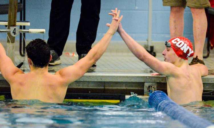 Waterville/Winslow's Eric Booth, left, and Cony's Gabe Biasuz clasp hands after competing in the 100-meter butterfly during a meet Friday at the Kennebec Valley YMCA in Augusta.