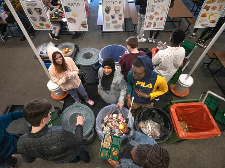 King Middle School eighth-graders Avalon Kuzma, Kawther Hlail and Jean David Bisimwa, left to right, help students sort their lunch items as they clear their trays at the end of a lunch period Wednesday. Students who assist with the sorting are known as "compost guardians" at the Portland school.