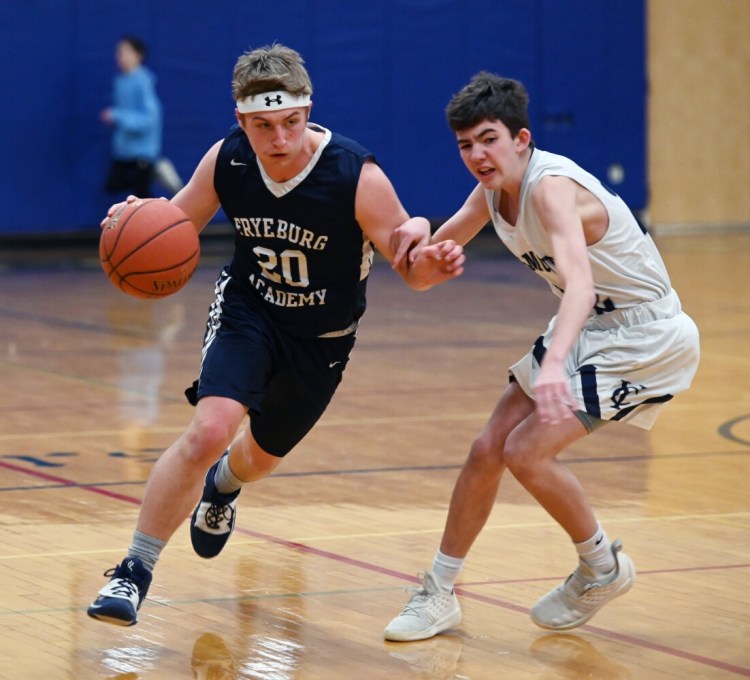 Fryeburg's Calvin Southwick dribbles up court while being defended by Yarmouth's Matt Waeldner on Friday in Yarmouth. Southwick made a 3-pointer to force overtime and the Raiders won 58-55. 