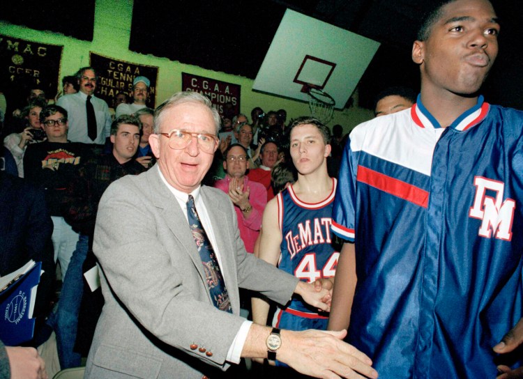 FILE - In this Jan. 22, 1993, file photo, DeMatha High School basketball coach Morgan Wootten walks from the bench after his 1,000th victory, in Alexandria, Va. Next to Wootten are DeMatha players Tim Strachan (44) and Steve Napper, right. Morgan Wootten, a Hall of Fame basketball coach who built DeMatha High School into a national powerhouse and mentored several future NBA stars during a career that spanned parts of six decades, has died.  He was 88. The school announced his death on Twitter, writing, “The Wootten Family is saddened to share the news that their loving husband and father Morgan Wootten passed away" on Tuesday night, Jan. 21, 2020. (AP Photos/Ted Mathias, File)