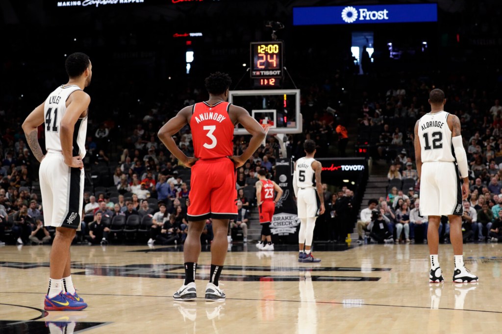 San Antonio Spurs players and Toronto Raptors players stop action during the first half of a basketball game to honor former NBA player Kobe Bryant, in San Antonio, Sunday, Jan. 26, 2020. Bryant died in a California helicopter crash Sunday. (AP Photo/Eric Gay)