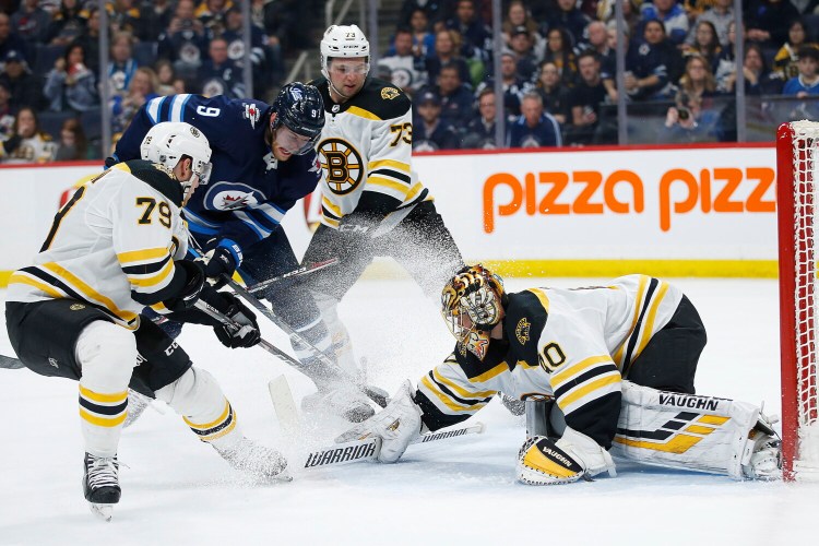 Winnipeg's Andrew Copp gets stopped by Boston  goaltender Tuukka Rask as Jeremy Lauzon, left, and Charlie McAvoy (73) defend during Friday's game in Winnipeg, Manitoba. ()