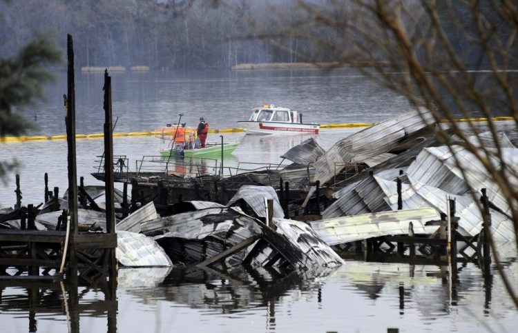 People on boats patrol near the charred remains of a dock following a fatal fire at a Tennessee River marina in Scottsboro, Ala., on Monday. Authorities said the explosive fire was reported overnight while people were sleeping on boats tied up at the structure. 