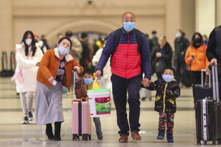 Travelers wearing face masks walk with their luggage at Hankou Railway Station in Wuhan in southern China's Hubei province. The U.S. on Tuesday reported its first case of a new and potentially deadly virus circulating in China.