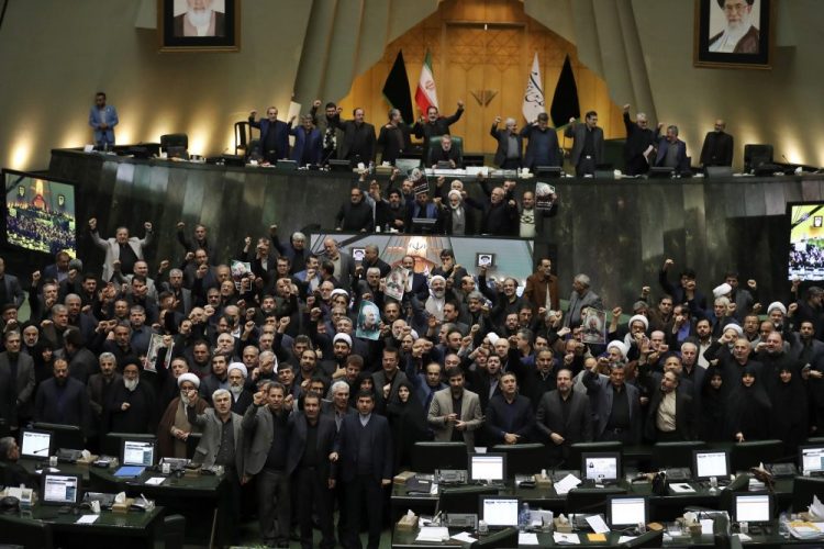 Iranian lawmakers chant slogans Tuesday as some of them hold posters of Gen. Qassem Soleimani in an open session of parliament. Iran's parliament passed an urgent bill declaring the U.S. military's command in Washington and those acting on its behalf "terrorists," subject to Iranian sanctions.