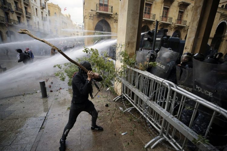 Anti-government demonstrators clash with riot police at a road leading to the parliament building in Beirut, Lebanon, on Saturday. Riot police fired tears gas and sprayed protesters with water cannons after riots broke out during a march against the ruling elite amid a severe economic crisis. 