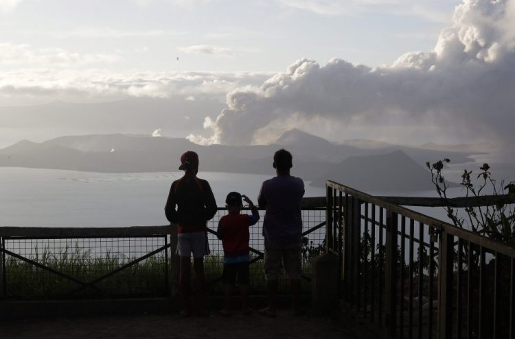 People watch from Tagaytay as Taal volcano continues to spew ash on Tuesday. Thousands of people fled the area through heavy ash as experts warned that the eruption could get worse and plans were being made to evacuate more.