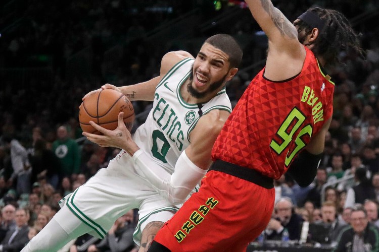 Jayson Tatum of the Celtics leans in as he drives against Atlanta's DeAndre' Bembry during Friday's game in Boston. 