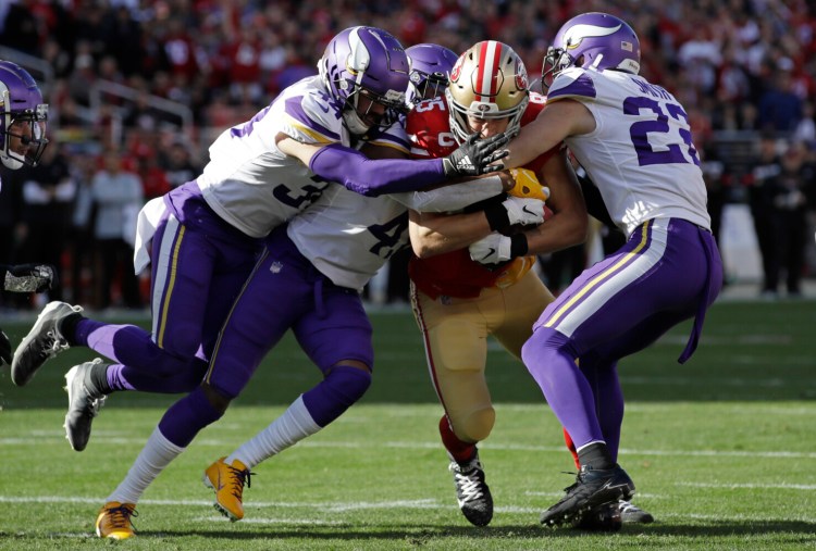 San Francisco tight end George Kittle, center, is tackled by Minnesota’s Harrison Smith, right, and other defenders during Saturday’s divisional playoff game. Kittle had just three catches for 16 yards, but the 49ers beat the Vikings, 27-10.