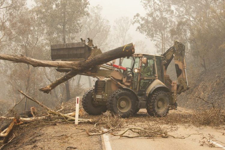 In this image released and dated on Jan. 6, 2020, from Australian Department of Defence, plant operators Cpl. Duncan Keith and Sapper Ian Larner of the 22nd Engineer Regiment use a 434 backhoe to assist staff from Forestry Management Victoria to clear fire damaged trees from the great Alpine road between Bairnsdale and Omeo during Operation Bushfire Assist 19-20 in Bairnsdale, Victoria, Australia. 