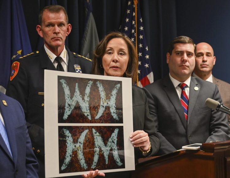 Suffolk County Police Commissioner Geraldine Hart shows a photograph with the initials on a belt, showing either an HM or WH, depending on the angle, during a press conference at police headquarters in Yaphank , N.Y., in January.