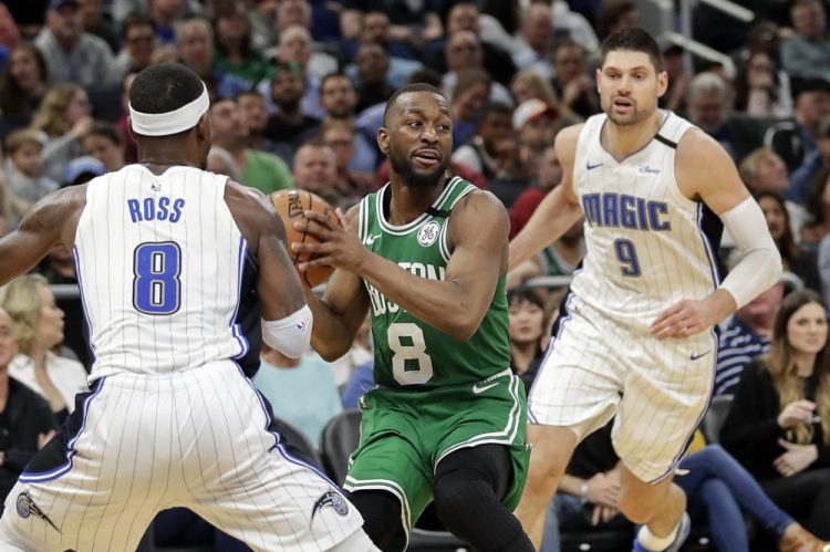 Celtics guard Kemba Walker, center, looks to pass the ball as he is defended by Orlando guard Terrence Ross, left, and center Nikola Vucevic during the Celtics' 109-98 win Friday in Orlando, Florida. Walker finished with 37 points.