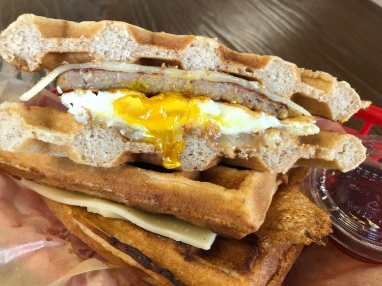 The Waffle is a breakfast sandwich with egg, sausage, cheddar cheese and maple syrup. 