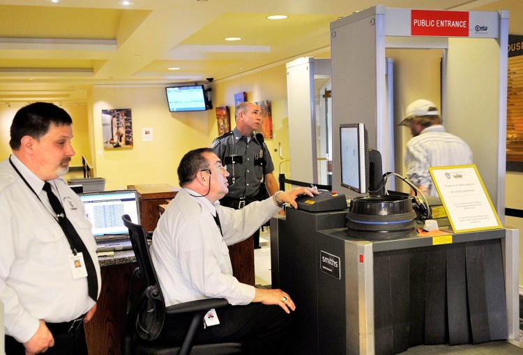 Capitol Police screeners review items while a visitor at the State House passes through a metal detector in 2013.