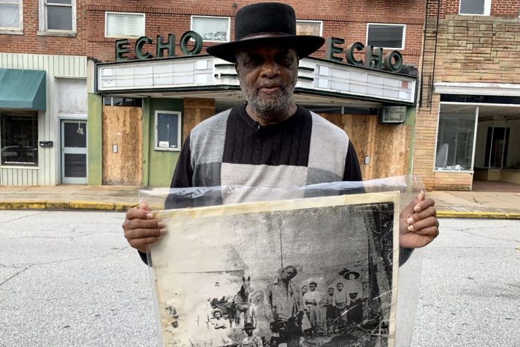 In this Monday, Jan. 13, 2020 photo, Rev. David Kennedy stands outside the Echo Theater holding a photo of his great uncle's lynching, in Laurens, S.C. Kennedy has fought for civil rights in South Carolina for decades. 
