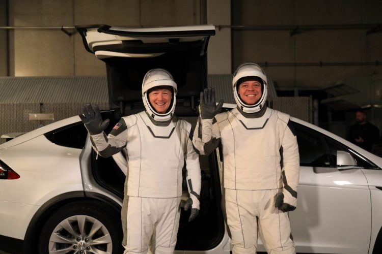 In this Friday, Jan. 17, 2020, photo provided by NASA, Astronauts Doug Hurley, left, and Robert Behnken pose in front of a Tesla Model X at a SpaceX event at Kennedy Space Center in Florida in January. Space X is owned by Elon Musk, the founder of Tesla. 