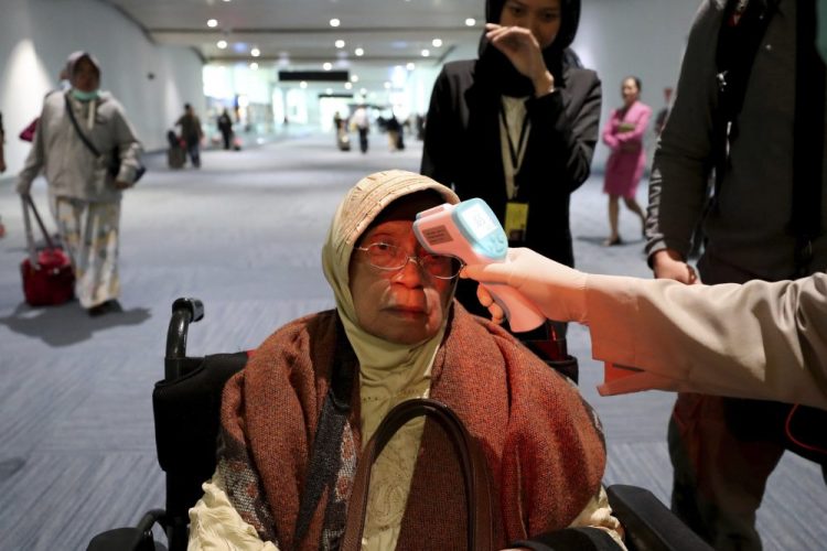 A health official scans the body temperature of a passenger as she arrives Wednesday at the Soekarno-Hatta International Airport in Tangerang, Indonesia. 