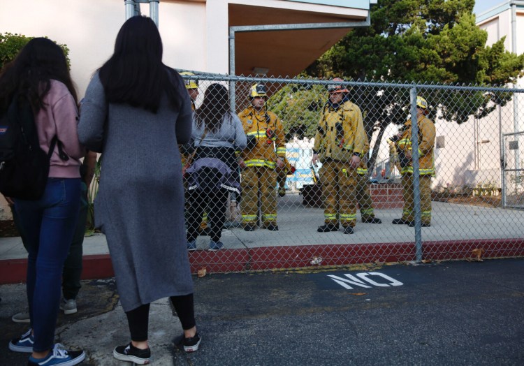 Parents wait outside Park Avenue Elementary School in Cudahy, Calif., after an airplane returning to Los Angeles International Airport dropped what was believed to be engine fuel onto a school playground Tuesday. 