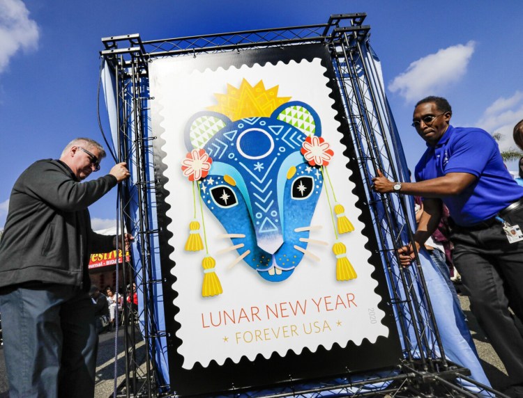 Michael Henry, left, and Charles Williams of the U.S. Postal Service with a replica of the Year of the Rat stamp at the Lunar New Year Festival in Monterey Park on Saturday. 