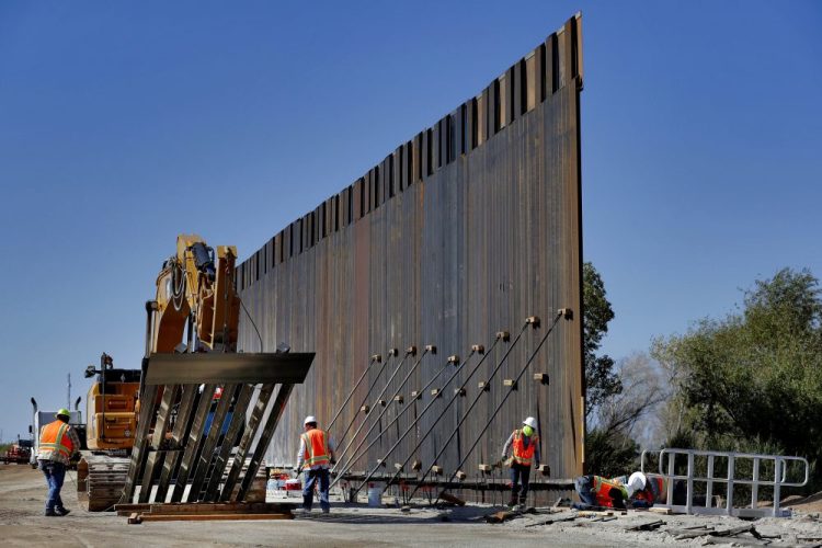 Government contractors erect a section of Pentagon-funded border wall along the Colorado River in Yuma, Ariz., in September. The White House says construction of the U.S.-Mexico border wall will move forward after a federal appeals court ruling that frees up construction money. 