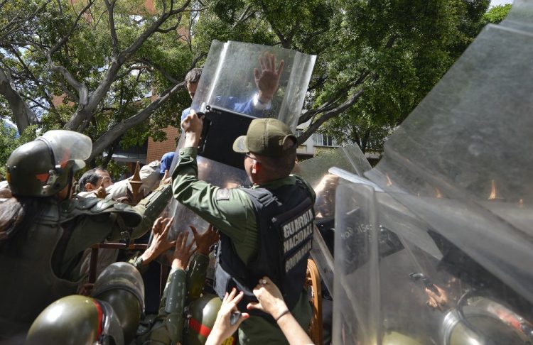 National Assembly President Juan Guaido, Venezuela's opposition leader, tries to climb the fence past National Guards to enter the compound of the Assembly on Sunday.