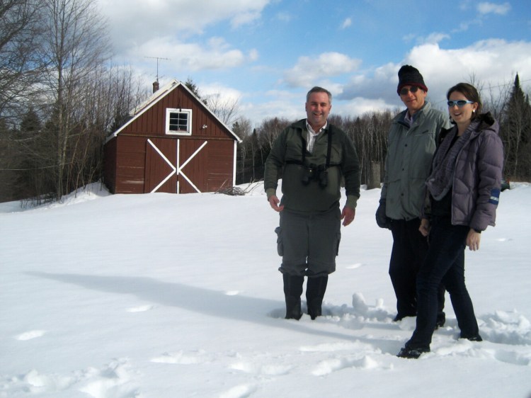 Jason Johnston, left, co-author of the paper on L.S. Quackenbush’s journal on the changing seasons, Richard Primack and Caitlin McDonough MacKenzie pose in front of Quackenbush's barn in Oxbow, Maine. 
